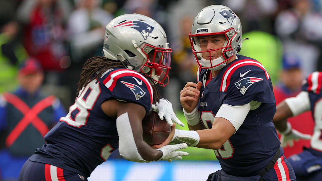 Nov 12, 2023; Frankfurt, Germany;  New England Patriots quarterback Mac Jones (10) hands off to running back Rhamondre Stevenson (38) against the Indianapolis Colts in the first quarter during an International Series game at Deutsche Bank Park. Mandatory Credit: Nathan Ray Seebeck-Imagn Images