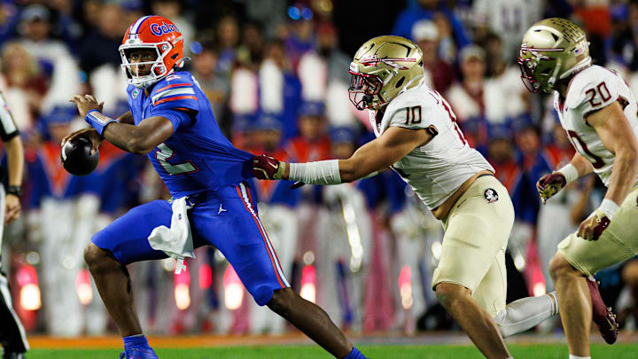 Nov 29, 2025; Gainesville, Florida, USA; Florida Gators quarterback DJ Lagway (2) runs with the ball while Florida State Seminoles defensive lineman James Williams (10) grabs his jersey during the first half at Ben Hill Griffin Stadium. Mandatory Credit: Matt Pendleton-Imagn Images