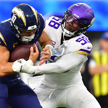 Oct 23, 2025; Inglewood, California, USA; Los Angeles Chargers quarterback Justin Herbert (10) ruses the ball against Minnesota Vikings linebacker Jonathan Greenard (58) during the first half at SoFi Stadium. Mandatory Credit: Gary A. Vasquez-Imagn Images
