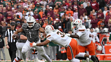 Nov 22, 2025; Blacksburg, Virginia, USA; Virginia Tech Hokies quarterback Kyron Drones (1) breaks a tackle from Miami (FL) Hurricanes defensive lineman Akheem Mesidor (3) during the first quarter at Lane Stadium. Mandatory Credit: Brian Bishop-Imagn Images