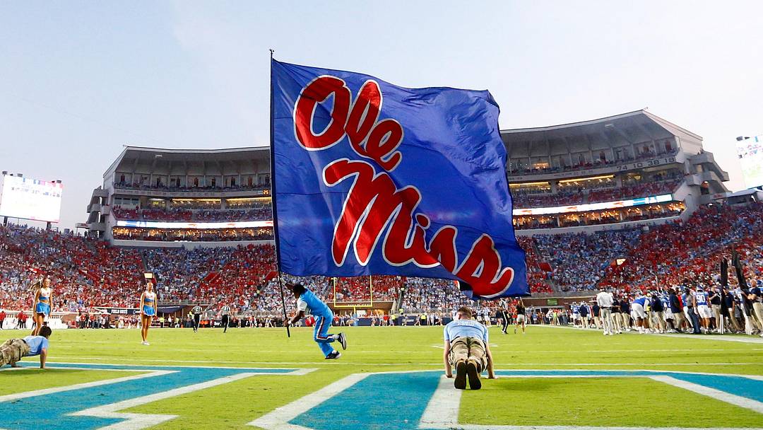 Sep 13, 2025; Oxford, Mississippi, USA; Mississippi Rebels cheerleaders run an Ole Miss flag across the field after a touchdown during the second quarter against the Arkansas Razorback at Vaught-Hemingway Stadium. Mandatory Credit: Petre Thomas-Imagn Images
