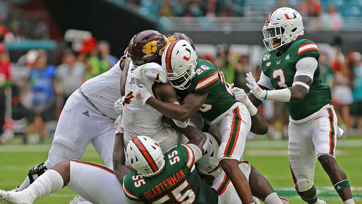 Sep 21, 2019; Miami Gardens, FL, USA; Central Michigan Chippewas running back Kobe Lewis (4) gets tackled by Miami Hurricanes linebacker Shaquille Quarterman (55) and Miami Hurricanes defensive back Gurvan Hall Jr. (26) during the first half of a football game at Hard Rock Stadium. Mandatory Credit: Sam Navarro-USA TODAY Sports