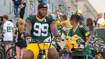 Green Bay Packers defensive end Barryn Sorrell (99) rides a young fan’s bicycle to practice at the Ray Nitschke Field during the second day of training camp on Thursday, July 24, 2025, in Ashwaubenon, Wis.