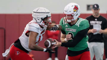 Louisville football quarterback Tyler Shough (9) and running back Peny Boone (13) run drills during spring practice.