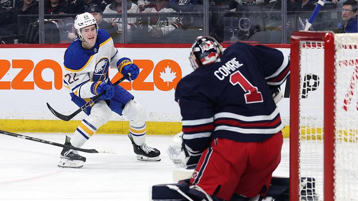 Mar 23, 2025; Winnipeg, Manitoba, CAN; Buffalo Sabres right wing Jack Quinn (22) takes a shot on Winnipeg Jets goaltender Eric Comrie (1) in the first period at Canada Life Centre. Mandatory Credit: James Carey Lauder-Imagn Images