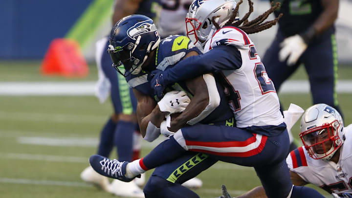 Sep 20, 2020; Seattle, Washington, USA; Seattle Seahawks wide receiver DK Metcalf (14) is tackled by New England Patriots cornerback Stephon Gilmore (24) and New England Patriots linebacker Anfernee Jennings (58) after making a reception during the second quarter at CenturyLink Field. Mandatory Credit: Joe Nicholson-Imagn Images