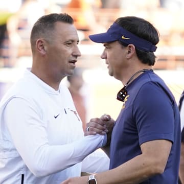 Texas Longhorns head coach Steve Sarkisian talks with West Virginia Mountaineers head coach Neal Brown before a game at Darrell K Royal-Texas Memorial Stadium.