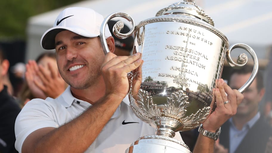 Brooks Koepka is handed the Wanamaker Trophy on the 18th green following his victory at the 2023 PGA Championship. 