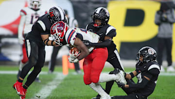 Aliquippa's QaLil Goode (14), Gavin Wilcox (13), and Arison Walker (15) attempt to hold back McKeesport's Kemon Spell (20) from scoring a touchdown during the second half of the WPIAL 4A Championship game Friday evening at Acrisure Stadium in Pittsburgh, PA.