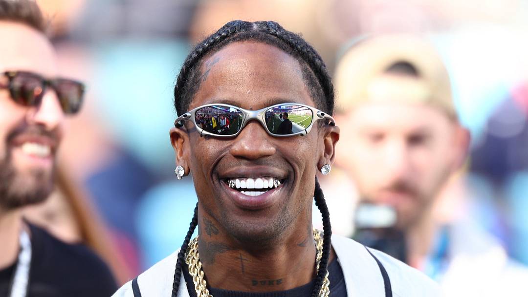 Travis Scott looks on from the sidelines before Super Bowl LX