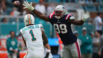 New England Patriots defensive end Keion White (99) reaches for the pass of Miami Dolphins quarterback Tua Tagovailoa (1) during the first half at Hard Rock Stadium.