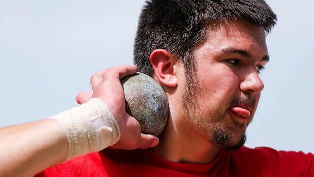 Jackson Cantwell spins around as he practices throwing a shotput during track and field practice at Nixa High School