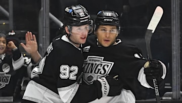Mar 22, 2025; Los Angeles, California, USA; Los Angeles Kings defenseman Brandt Clarke (92) and left wing Trevor Moore (12) celebrate after scoring against the Carolina Hurricanes during the second period at Crypto.com Arena. Mandatory Credit: Jonathan Hui-Imagn Images