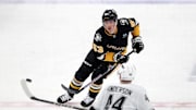 Dec 17, 2024; Pittsburgh, Pennsylvania, USA; Pittsburgh Penguins center Philip Tomasino (53) flips the puck up ice against Los Angeles Kings defenseman Mikey Anderson (44) during the second period at PPG Paints Arena. Mandatory Credit: Charles LeClaire-Imagn Images