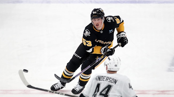 Dec 17, 2024; Pittsburgh, Pennsylvania, USA; Pittsburgh Penguins center Philip Tomasino (53) flips the puck up ice against Los Angeles Kings defenseman Mikey Anderson (44) during the second period at PPG Paints Arena. Mandatory Credit: Charles LeClaire-Imagn Images