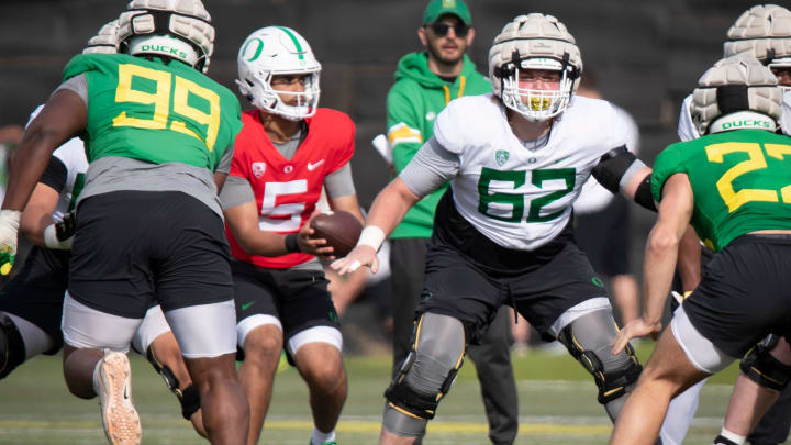 Oregon quarterback Dante Moore takes a snap from lineman Holden Whipple during practice with the Ducks Thursday, April 11, 2024, at the Hatfield-Dowlin Complex in Eugene, Ore.