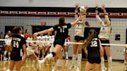Assumption High School middle Carle Hooe taps the ball between two Sacred Heart High School blockers Nov. 1, 2025, in the 7th Region Championship match.