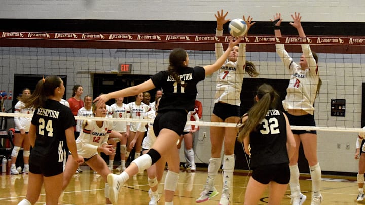 Assumption High School middle Carle Hooe taps the ball between two Sacred Heart High School blockers Nov. 1, 2025, in the 7th Region Championship match. Assumption High School middle Carle Hooe taps the ball between two Sacred Heart High School blockers Nov. 1, 2025, in the 7th Region Championship match.