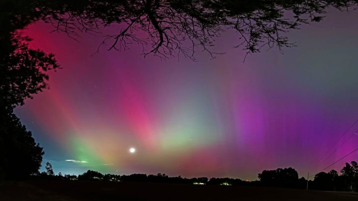 A rare southern display of the aurora borealis or 'northern lights' colors the sky over a farm field just north of Stedman, North Carolina on the evening of Friday, May 10, 2024. The bright object near the horizon is the moon. Solar activity, which can trigger aurora displays, is ramping up so future auroral displays are possible, in the coming months, even from southerly latitudes.