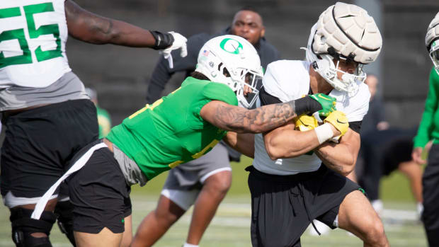 Oregon running back Jayden Limar attempts to break a tackle by defensive back Kobe Savage during practice