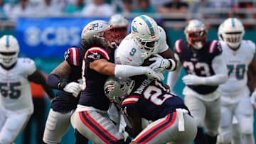 Nov 24, 2024; Miami Gardens, Florida, USA; New England Patriots linebacker Jahlani Tavai (48) and safety Jaylinn Hawkins (21) attempt to tackle Miami Dolphins tight end Jonnu Smith (9) during the first half at Hard Rock Stadium. Mandatory Credit: Jasen Vinlove-Imagn Images