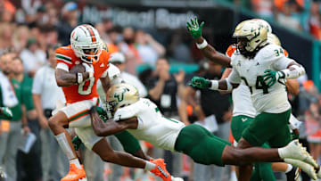 Sep 13, 2025; Miami Gardens, Florida, USA; Miami Hurricanes wide receiver Keelan Marion (0) runs with the football against South Florida Bulls linebacker Jhalyn Shuler (7) during the first quarter at Hard Rock Stadium. Mandatory Credit: Sam Navarro-Imagn Images