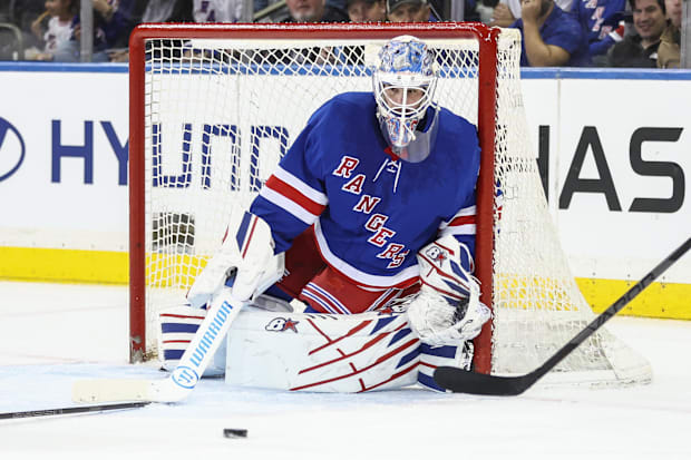 Hockey goalie in blue uniform defends the ne