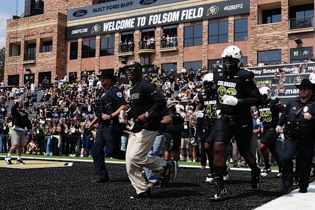 Sep 6, 2025; Boulder, Colorado, USA; Colorado Buffaloes head coach Deion Sanders (center) leads the team onto Folsom Field be