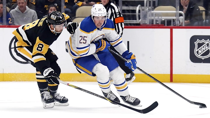 Oct 16, 2024; Pittsburgh, Pennsylvania, USA; Buffalo Sabres defenseman Owen Power (25) moves the puck ahead of Pittsburgh Penguins left wing Michael Bunting (8) during the third period at PPG Paints Arena. Mandatory Credit: Charles LeClaire-Imagn Images