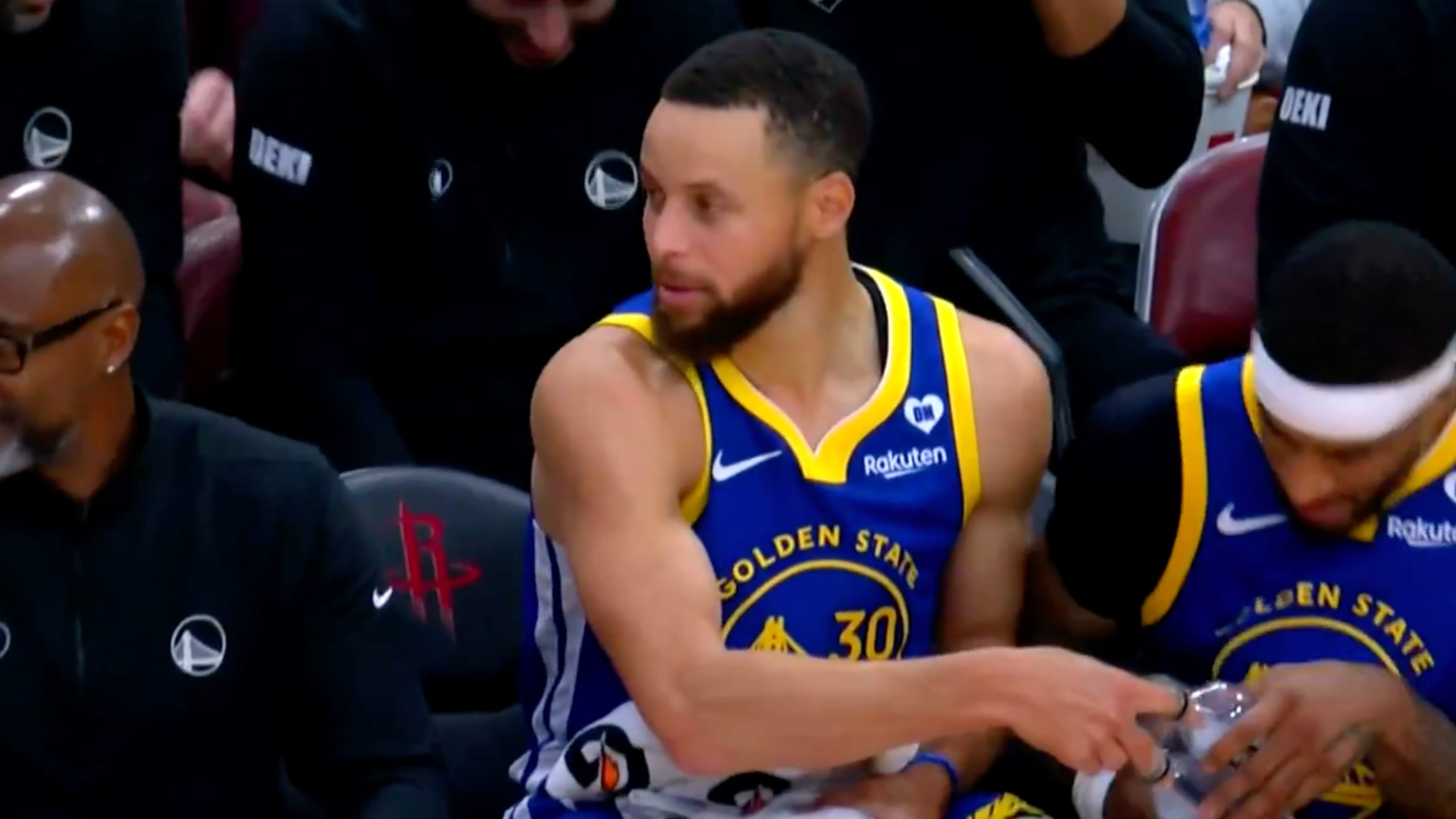Steph Curry celebrates a basket on the bench in unique fashion.