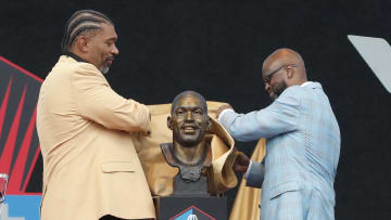 Aug 3, 2024; Canton, OH, USA;  Julius Peppers (left) and his presenter Carl Carey (right) unveil the bust of Peppers as he is inducted into the Pro Football Hall of Fame at the enshrinement ceremony at Tom Benson Hall of Fame Stadium. Mandatory Credit: Charles LeClaire-USA TODAY Sports