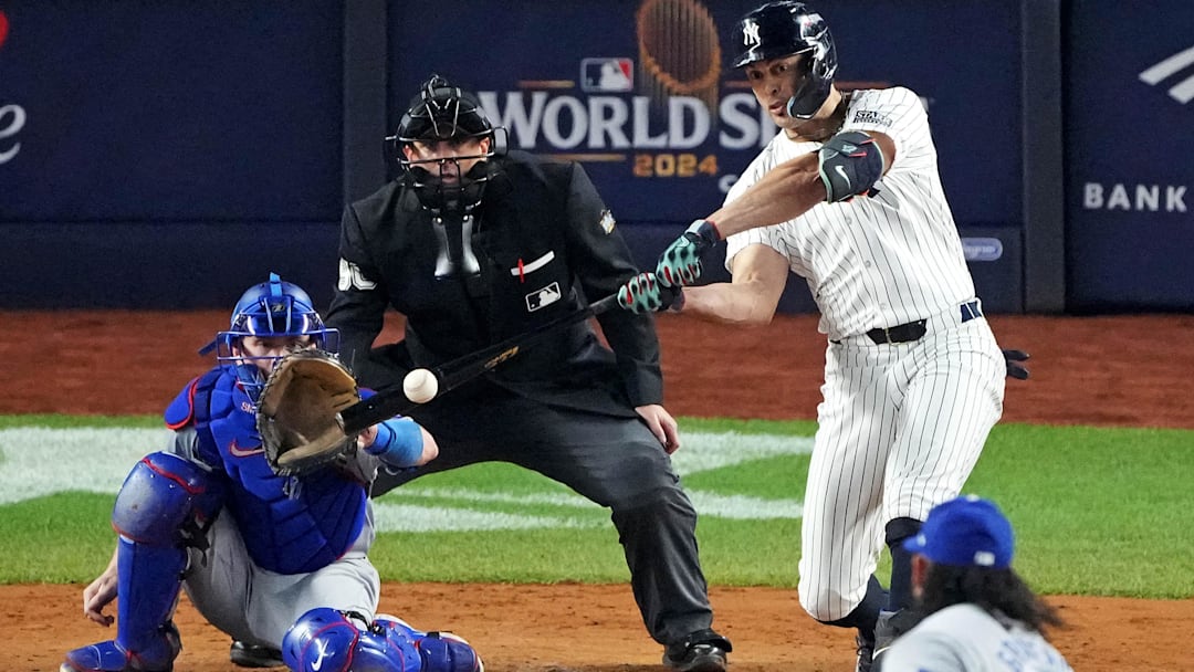 Oct 30, 2024; New York, New York, USA; New York Yankees designated hitter Giancarlo Stanton (27) hits an RBI sacrifice fly during the sixth inning against the Los Angeles Dodgers in game four of the 2024 MLB World Series at Yankee Stadium. 