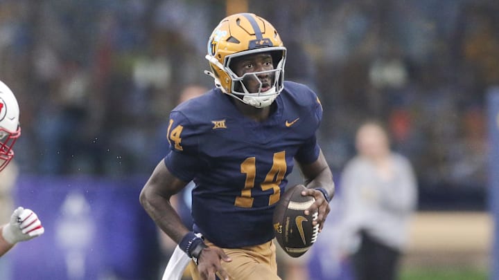 Sep 27, 2025; Morgantown, West Virginia, USA; West Virginia Mountaineers quarterback Khalil Wilkins (14) runs away from Utah Utes defensive end John Henry Daley (90) during the third quarter at Milan Puskar Stadium. Mandatory Credit: Ben Queen-Imagn Images Sep 27, 2025; Morgantown, West Virginia, USA; West Virginia Mountaineers quarterback Khalil Wilkins (14) runs away from Utah Utes defensive end John Henry Daley (90) during the third quarter at Milan Puskar Stadium. Mandatory Credit: Ben Queen-Imagn Images