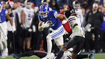 Nov 16, 2024; Provo, Utah, USA; Brigham Young Cougars wide receiver Chase Roberts (2) breaks a tackle by Kansas Jayhawks safety Taylor Davis (bottom) and safety Marvin Grant (4) defends during the fourth quarter at LaVell Edwards Stadium. Mandatory Credit: Rob Gray-Imagn Images