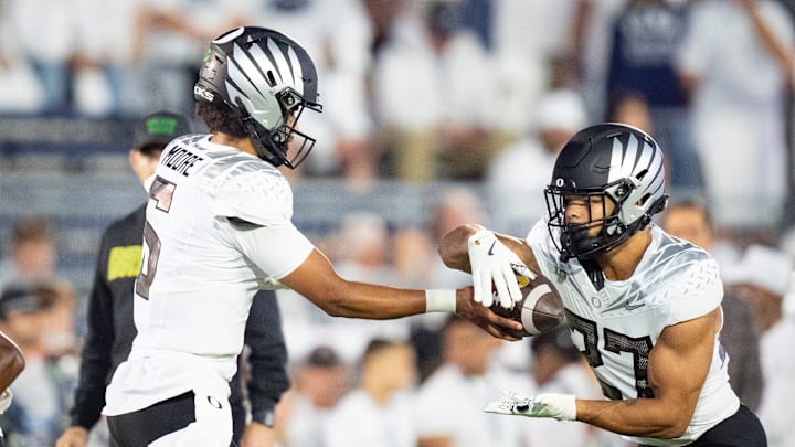 Oregon quarterback Dante Moore, left, hands off the ball to Oregon running back Jayden Limar during warmups as the Oregon Ducks face the Penn State Nittany Lions on Sept. 27, 2025, at Beaver Stadium in University Park, Pennsylvania.