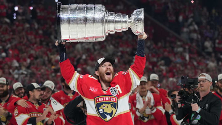 Jun 17, 2025; Sunrise, Florida, USA; Florida Panthers left wing Matthew Tkachuk (19) hoist the Stanley Cup after game six of the 2025 Stanley Cup Final against the Edmonton Oilers at Amerant Bank Arena. Mandatory Credit: Jim Rassol-Imagn Images