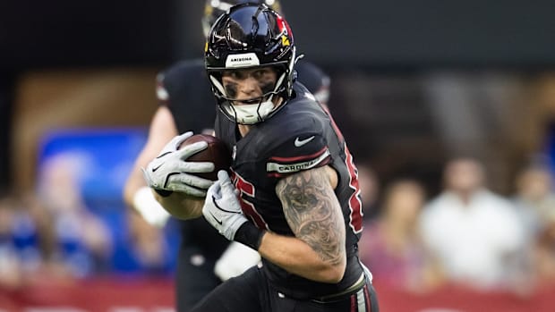 Cardinals tight end Trey McBride (black and red jersey) looks to run after securing a catch.