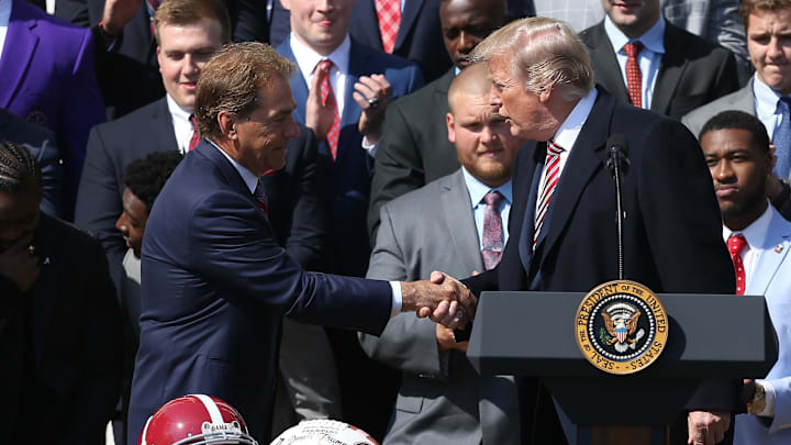 Apr 10, 2018; Washington, DC, USA; President Donald Trump (R) shakes hands with Alabama Crimson Tide head coach Nick Saban (L) listens along with players at a ceremony honoring the college football playoff champion Crimson Tide on the South Lawn at the White House. Mandatory Credit: Geoff Burke-Imagn Images
