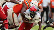 Nov 15, 2025; Miami Gardens, Florida, USA; NC State Wolfpack quarterback CJ Bailey (11) is tackled by Miami Hurricanes defensive lineman Armondo Blount (18) during the second quarter at Hard Rock Stadium. Mandatory Credit: Sam Navarro-Imagn Images
