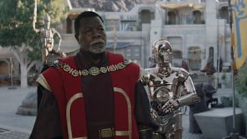 (L-R): Greef Karga (Carl Weathers) and Nevarro copper droid (Chris Bartlett) in Lucasfilm's THE MANDALORIAN, season three, exclusively on Disney+. ©2023 Lucasfilm Ltd. & TM. All Rights Reserved.