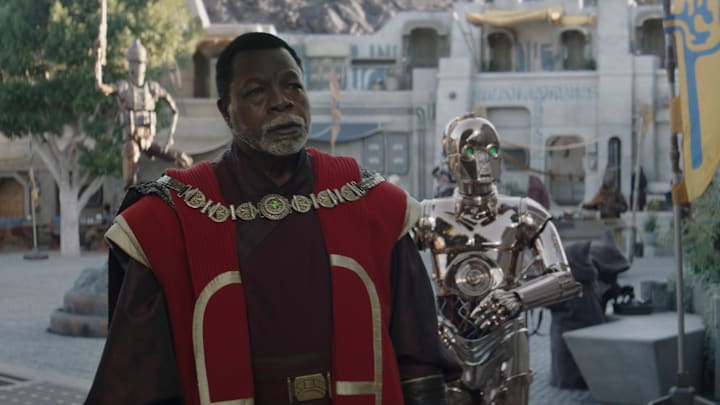 (L-R): Greef Karga (Carl Weathers) and Nevarro copper droid (Chris Bartlett) in Lucasfilm's THE MANDALORIAN, season three, exclusively on Disney+. ©2023 Lucasfilm Ltd. & TM. All Rights Reserved.
