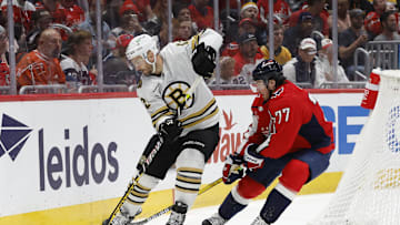 Apr 15, 2024; Washington, District of Columbia, USA; Boston Bruins defenseman Kevin Shattenkirk (12) skates with the puck as Washington Capitals right wing T.J. Oshie (77) defends in the third period at Capital One Arena. Mandatory Credit: Geoff Burke-Imagn Images