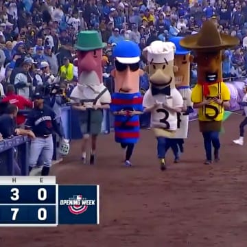 Byron Buxton walks onto the field as the Famous Racing Sausages at American Family Field sprint past.