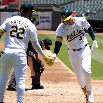 Jun 22, 2024; Oakland, California, USA; Oakland Athletics center fielder JJ Bleday (33) gets a congratulatory handshake from teammate Miguel Andujar (22) after hitting a solo home run against the Minnesota Twins during the first inning at Oakland-Alameda County Coliseum. Mandatory Credit: D. Ross Cameron-USA TODAY Sports