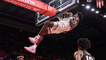 Nov 14, 2025; Piscataway, New Jersey, USA; Rutgers Scarlet Knights center Emmanuel Ogbole (21) hangs on the rim after dunking the ball during the second half against the Lehigh Mountain Hawks at Jersey Mike's Arena. Mandatory Credit: Vincent Carchietta-Imagn Images