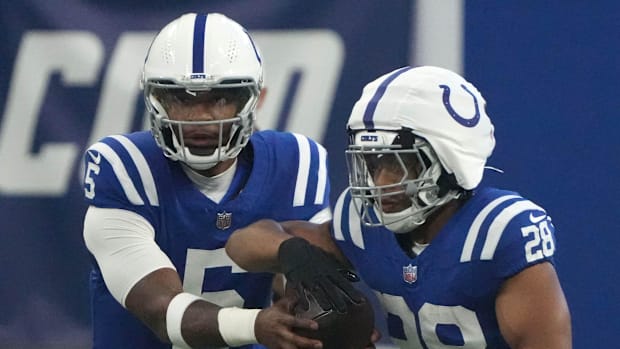 Colts running back Jonathan Taylor (blue jersey; white cap/helmet) takes a handoff from his quarterback. 