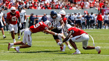 Sep 6, 2025; Raleigh, North Carolina, USA; Virginia Cavaliers tight end Sage Ennis (0) is tackled by North Carolina State Wolfpack safety Brody Barnhardt (29), cornerback Brian Nelson II (7) and cornerback Jackson Vick (22) during the first half of the game at Carter-Finley Stadium. Mandatory Credit: Jaylynn Nash-Imagn Images