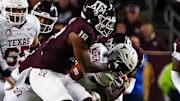 Nov 30, 2024; College Station, Texas, USA; Texas A&M defensive lineman Cashius Howell (18) grabs the face mask of Texas Longhorns running back Quintrevion Wisner (26) during the Lone Star Showdown at Kyle Field. Mandatory Credit: Sara Diggins/USA TODAY Network via Imagn Images
