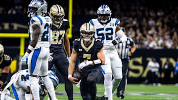 Sep 8, 2024; New Orleans, Louisiana, USA;  New Orleans Saints quarterback Taysom Hill (7) makes a first down against Carolina Panthers safety Nick Scott (21) during the first half at Caesars Superdome. Mandatory Credit: Stephen Lew-Imagn Images