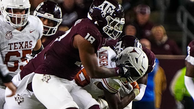 Texas A&M defensive lineman Cashius Howell grabs the face mask of Texas Longhorns running back Quintrevion Wisner.